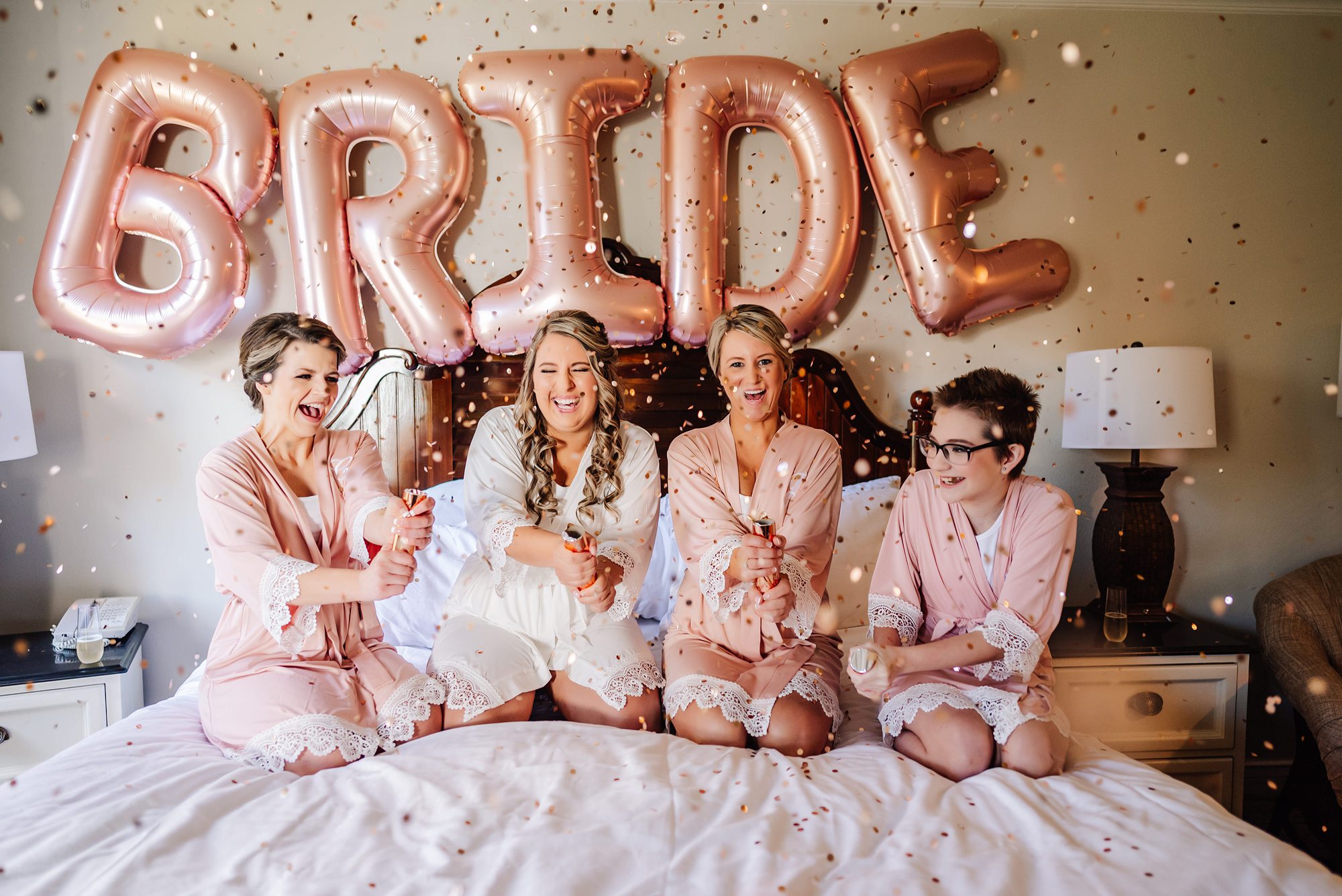 bridal party celebrating with confetti in matching robes
