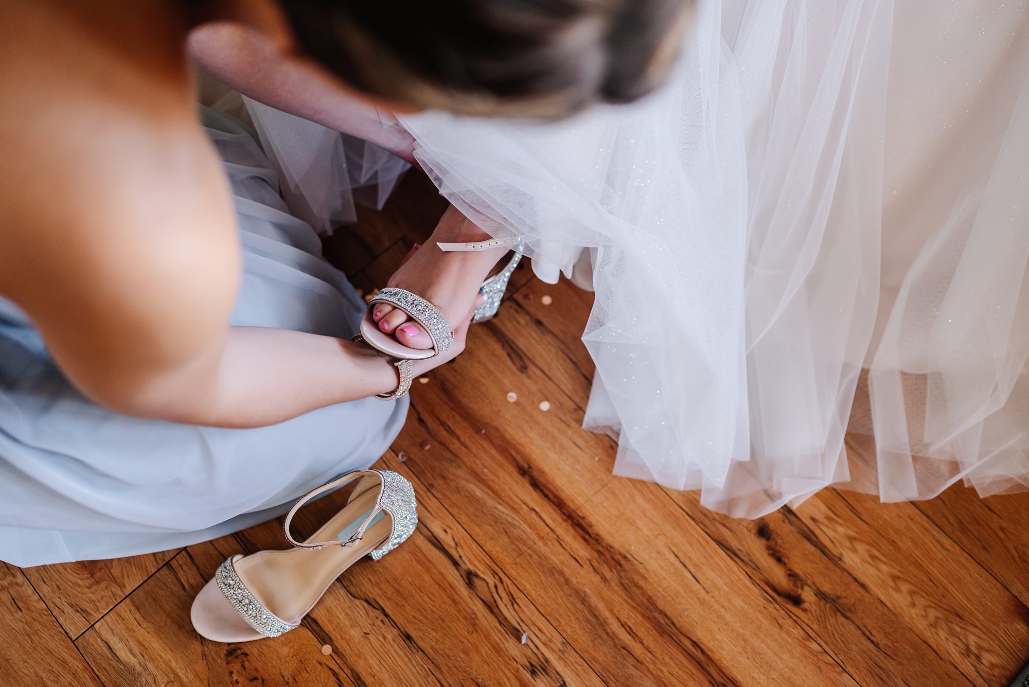 maid of honor putting brides shoes on