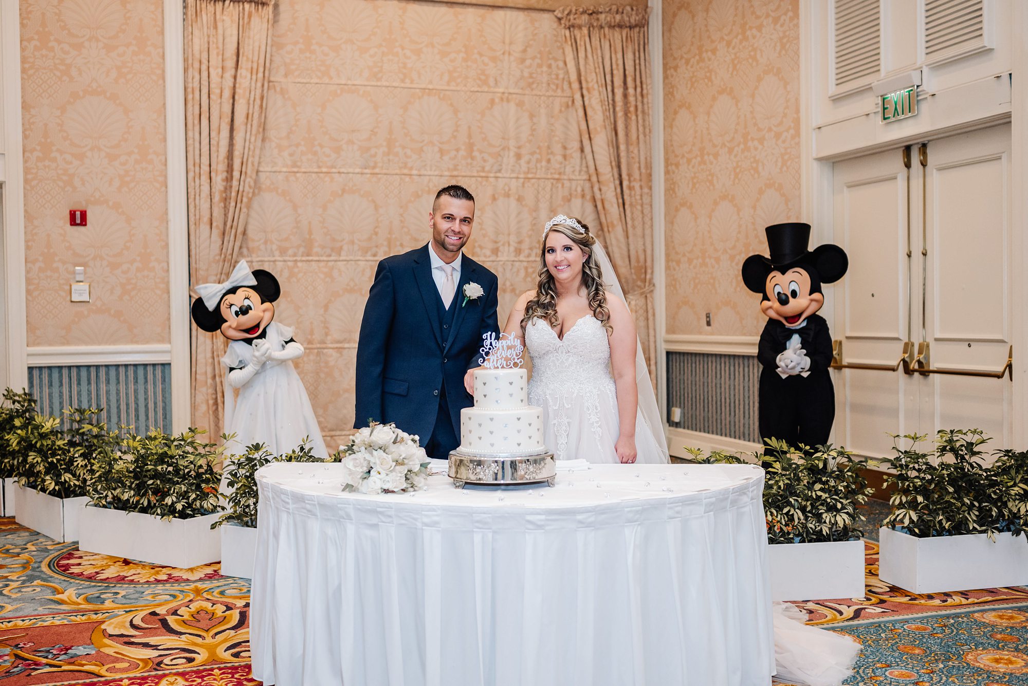 bride and groom cutting cake with mickey and Minnie Mouse