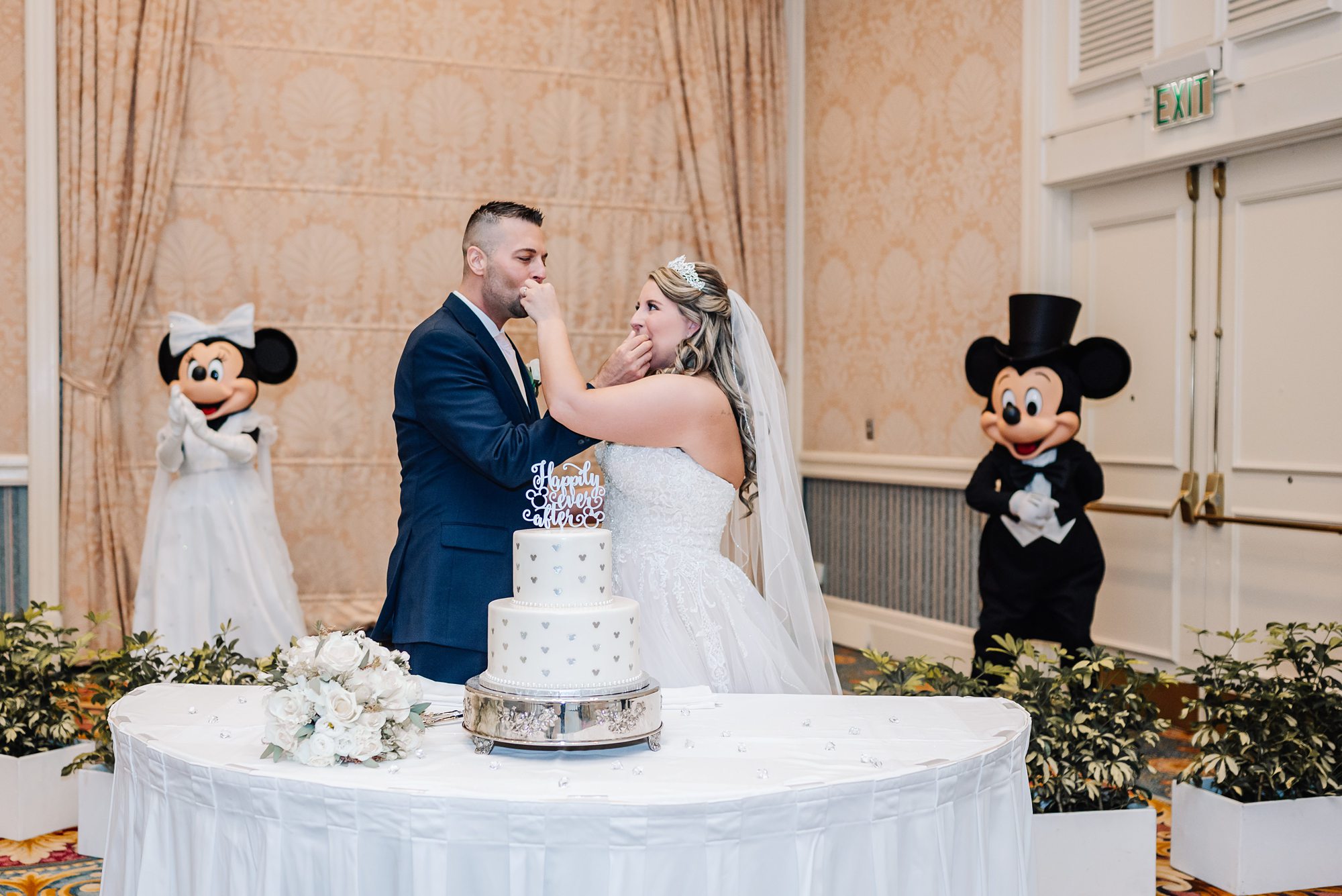 bride and groom eating cake with mickey and Minnie Mouse