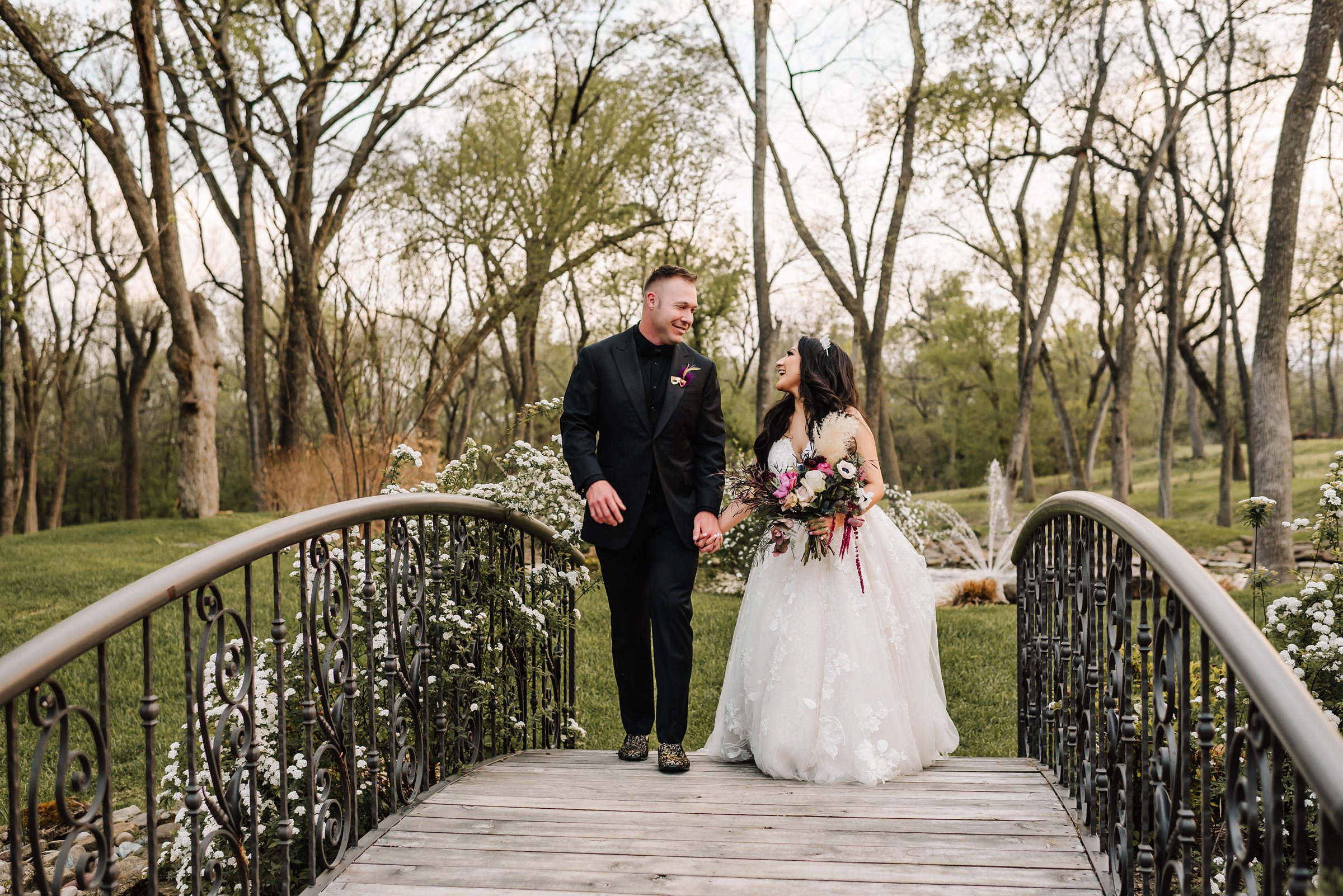 bride and groom walking on bridge in woods