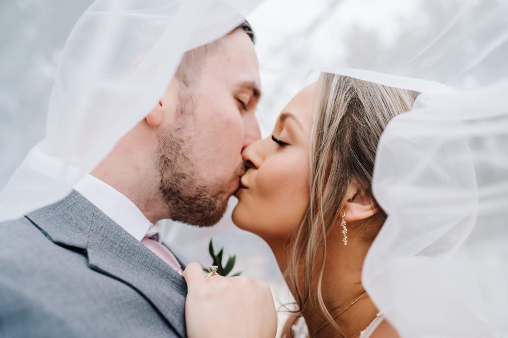 bride and groom kissing under veil at French farmhouse venue