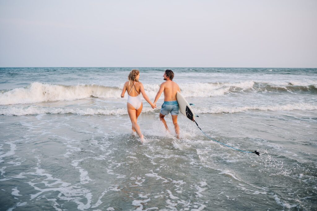 playful folly beach engagement photos with surfboard